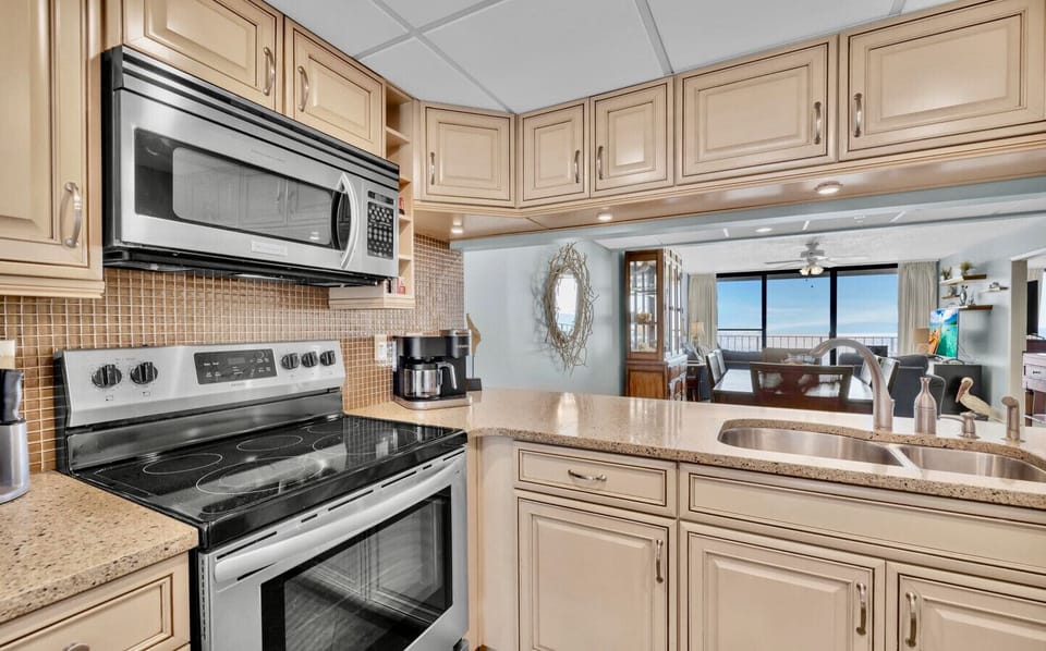 The fully equipped kitchen features stainless steel appliances, granite countertops, and a direct view of the Gulf through the open-concept living space.          Ask ChatGPT