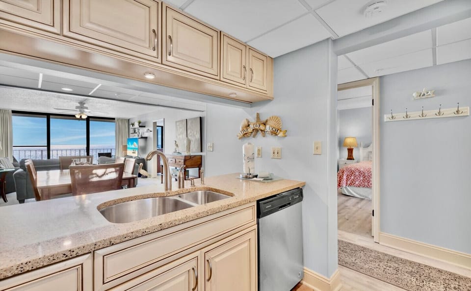 The fully equipped kitchen features stainless steel appliances, granite countertops, and a direct view of the Gulf through the open-concept living space.          Ask ChatGPT