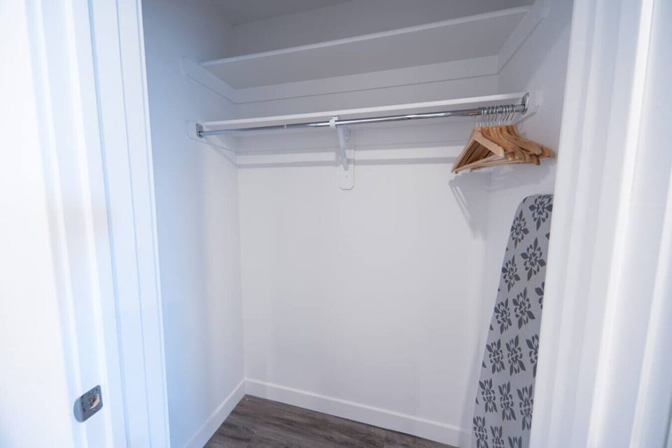Walk-in closet with dresser. Iron and Ironing board. Clothes drying rack.