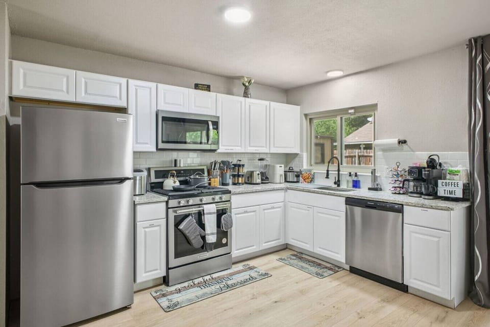 Cook with ease in this fully equipped modern kitchen featuring stainless steel appliances, sleek white cabinetry, and a cozy coffee station—bright, clean, and perfect for whipping up meals or enjoying your morning brew.