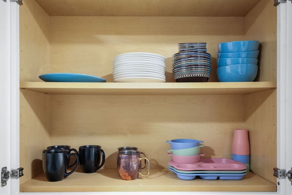 Fully stocked kitchen cabinet with a colorful variety of plates, bowls, mugs, and cups - perfect for families or extended stays. Everything you need for casual meals, coffee breaks, or kid-friendly dining is ready and waiting.