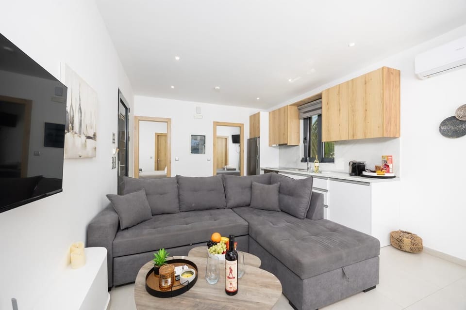 Open-plan living room with sofa, kitchen, A/C, WiFi internet, and satellite TV