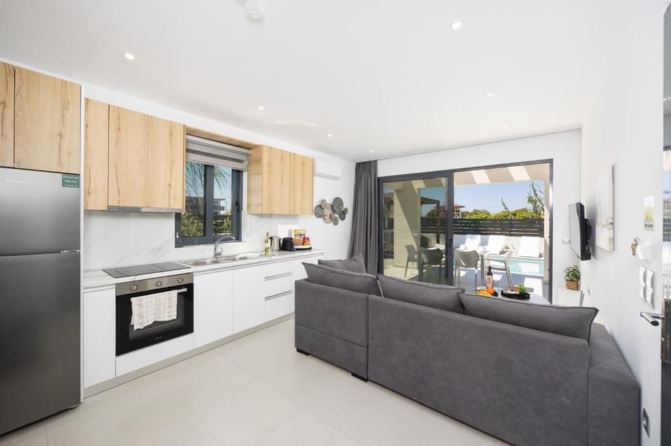Open-plan living room with sofa, kitchen, A/C, WiFi internet, and satellite TV