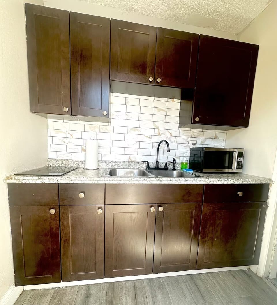 Kitchen equipped with two burners, blender, toaster, microwave and utensils.