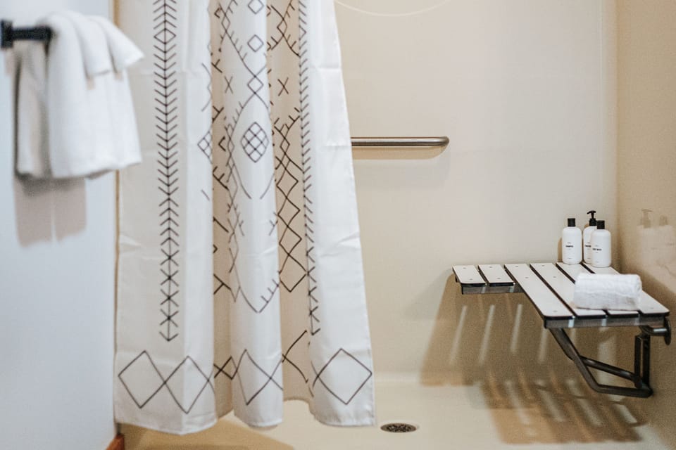Spacious walk-in shower with bench and grab bar for comfort and accessibility.