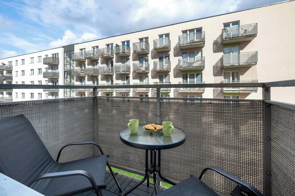 Outdoor seating area on a balcony overlooking a modern apartment complex.