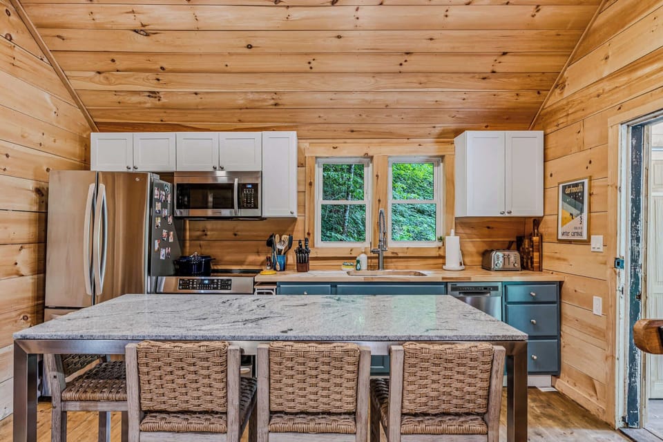 Kitchen island with four woven bar stools and fully equipped kitchen