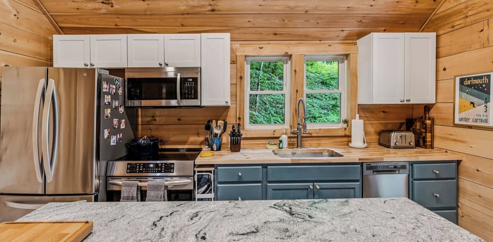 Full kitchen with blue cabinets, butcher block counters, and forest views