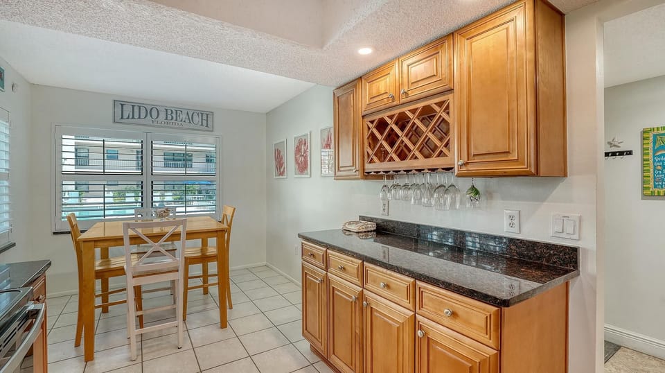Butler’s pantry with granite countertop, built-in honey oak cabinets, wine rack, and hanging glassware.