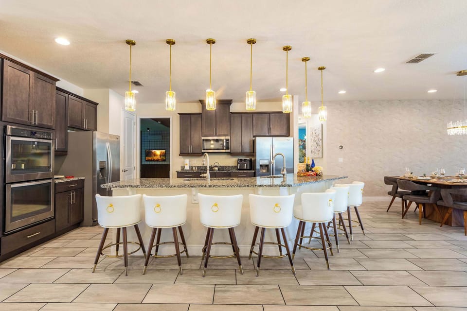The chef's kitchen anchors the home — a seven-seat island beneath designer pendants, double wall ovens, and the kind of counter space that turns morning coffee into a leisurely affair.