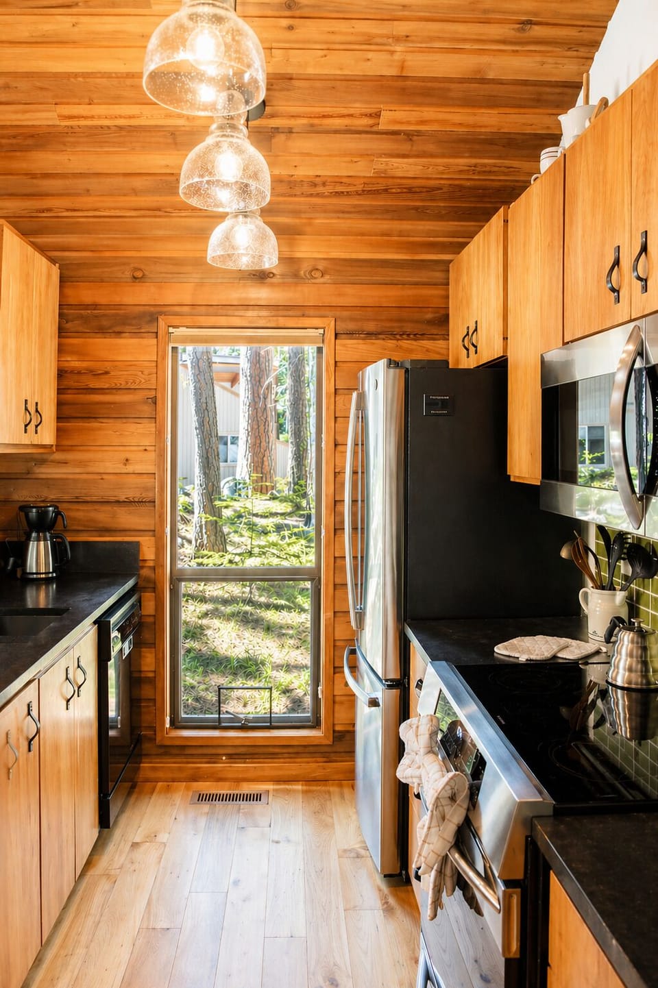 Your full kitchen features beautiful wood accents, modern appliances, and a door opening to wooded views—perfect for preparing meals in a cozy, cabin-inspired retreat.