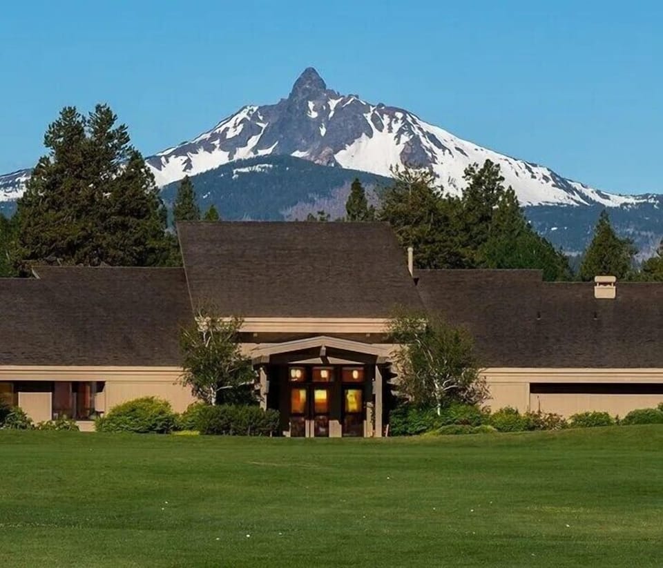 Roberts Pub set against snow-capped peaks with manicured grounds and forest surroundings.