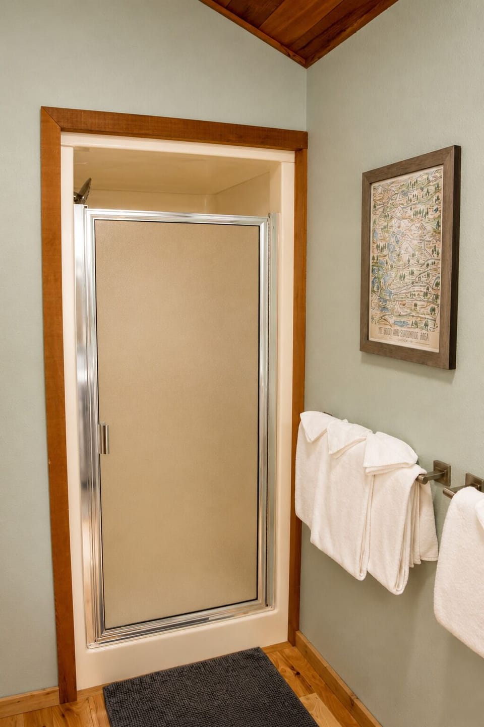 Step into your private en-suite bathroom with a spacious walk-in shower, complete with plush towels and warm wood accents for a cozy, home-like experience.