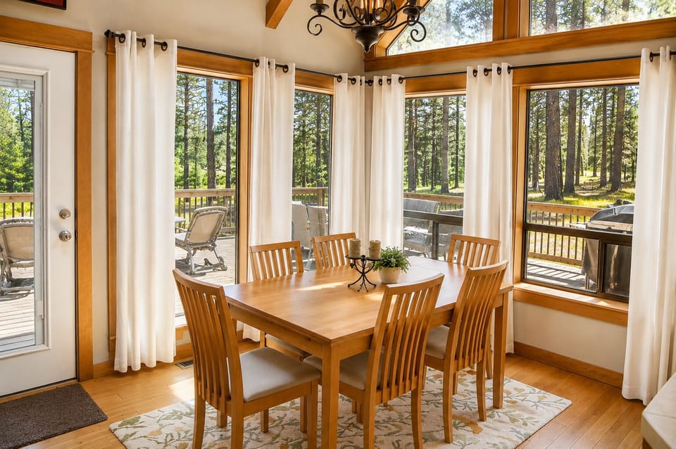 Gather around this bright dining table with forest views on all sides. Natural light fills your space through floor-to-ceiling windows. Step outside to your private deck anytime.