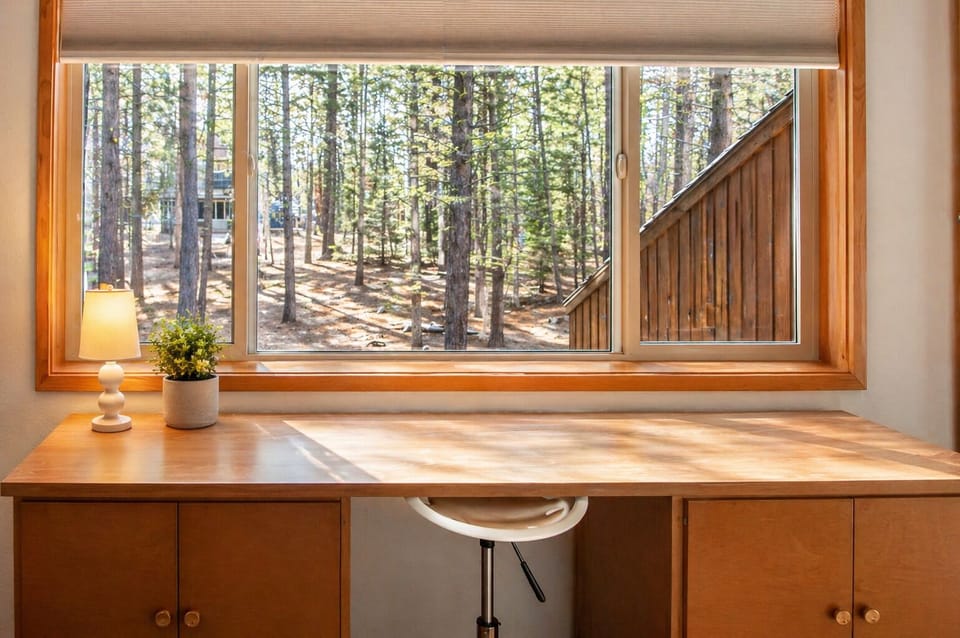 Your private workspace overlooks peaceful forest views, where natural light streams across warm wood surfaces creating an inspiring work retreat.