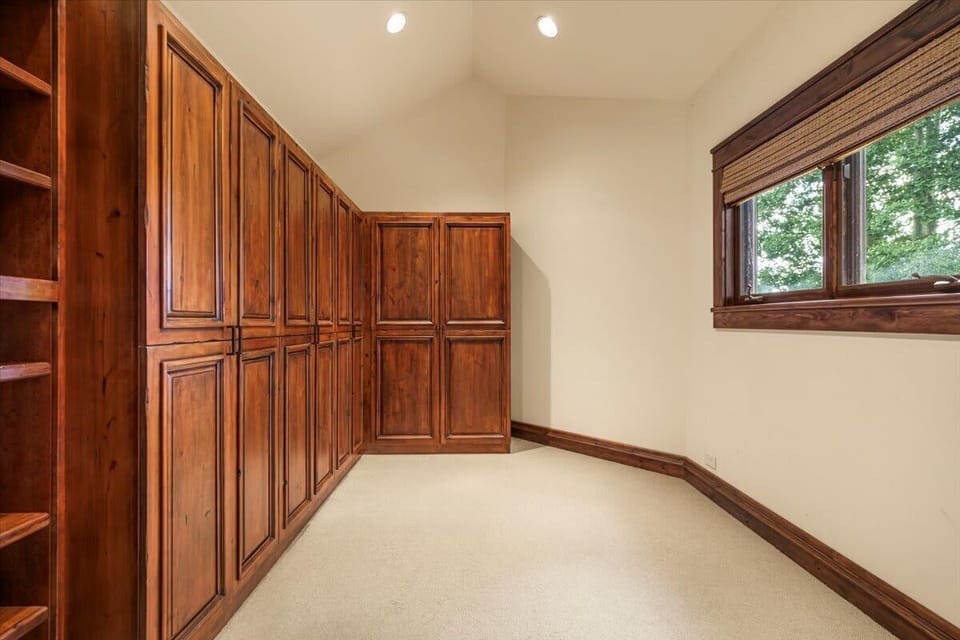 Closet: Spacious walk-in closet with custom wood cabinetry, built-in shelving, and natural light