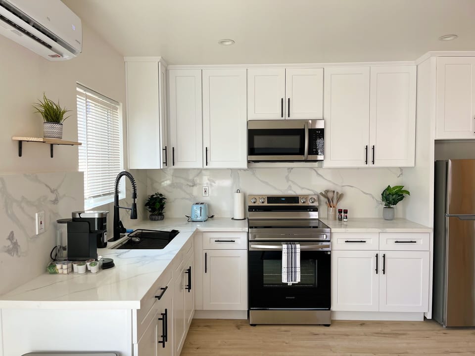 Full kitchen with electric stove, microwave, toaster, coffee maker, and more.