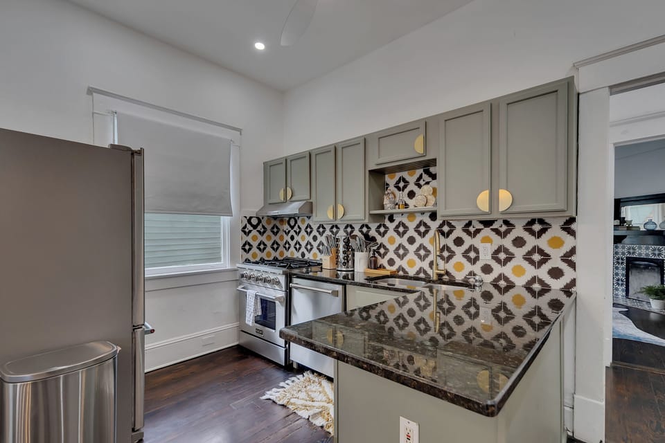 Stylish kitchen w/ patterned tile backsplash, sleek counters & modern appliances