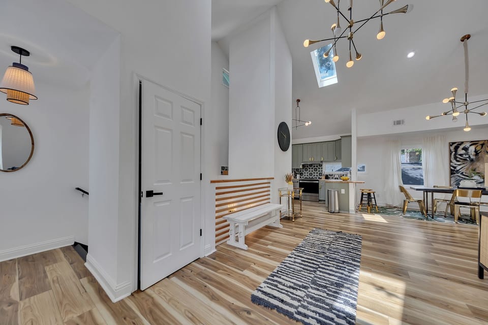Entry hallway w/ bench seating, wood floors & open sightlines into the airy living space