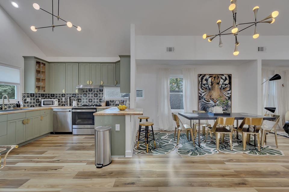 Open dining & kitchen layout ideal for gathering, w/ stylish lighting overhead