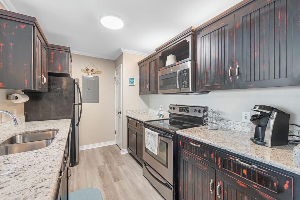 Your fully equipped kitchen features granite countertops, stainless steel appliances, and rich dark cabinetry for preparing memorable meals together.