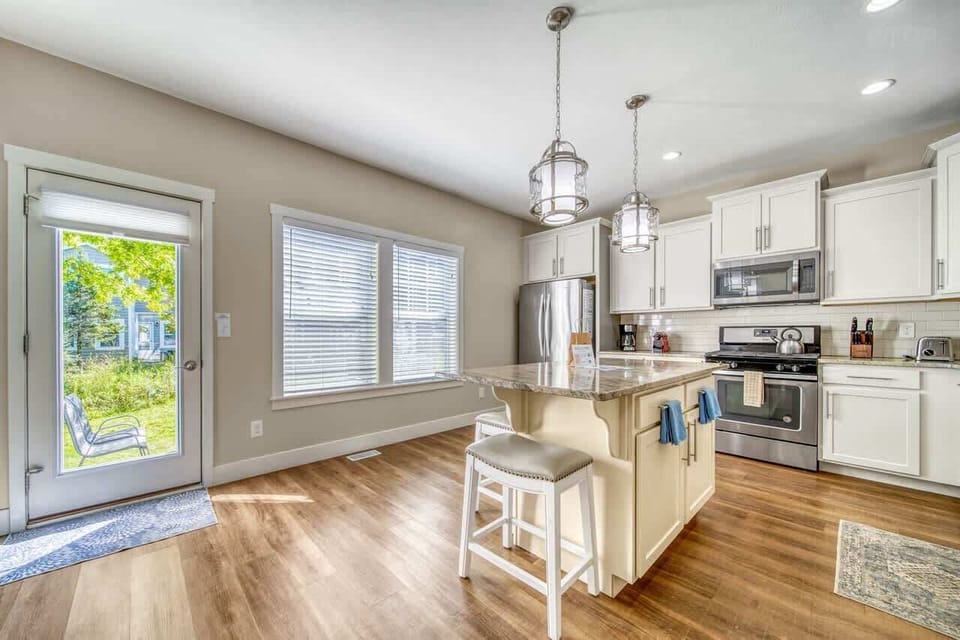 Bright and airy gourmet kitchen is open to the separate dining room and living room. Door exits to patio with outdoor seating, grill, and shared firepit