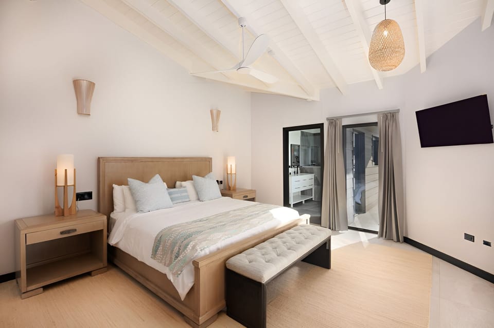 Unwind in airy comfort beneath beams and soft bedside glow.