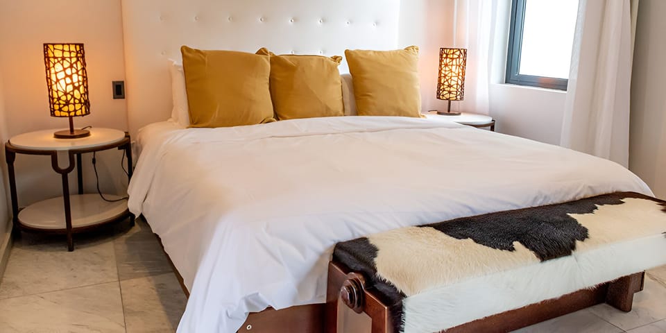 Unwind into crisp linens beneath warm, ambient bedside glow.