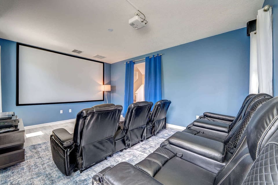 Home theater room with leather recliners and a large projector screen for an immersive viewing experience.
