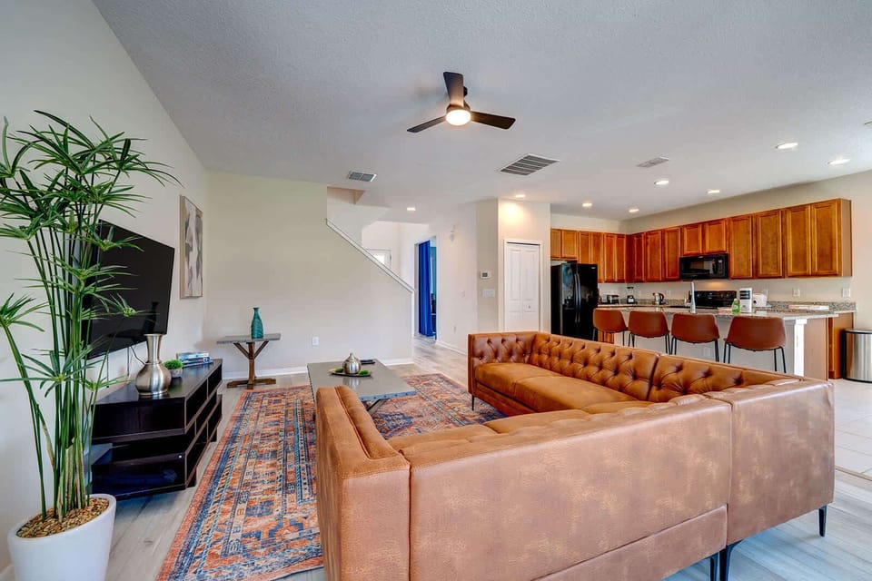 Spacious living area with a large leather sectional and open kitchen featuring a breakfast bar.