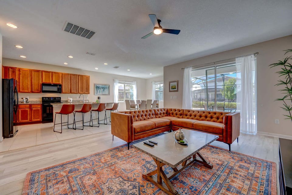Open-concept living area with a leather sectional and kitchen bar seating.