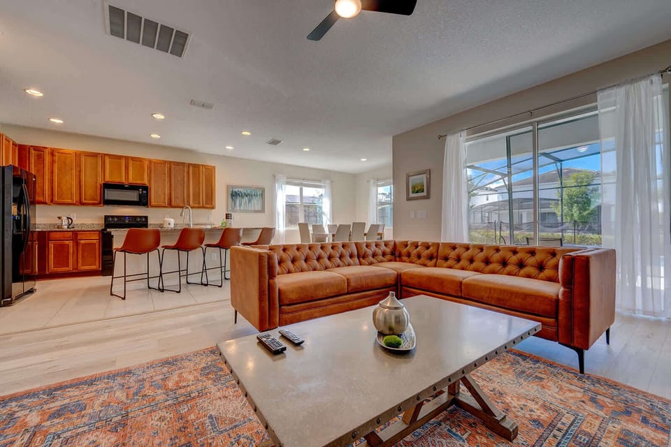 Open-concept living area with a leather sectional and natural light from large windows
