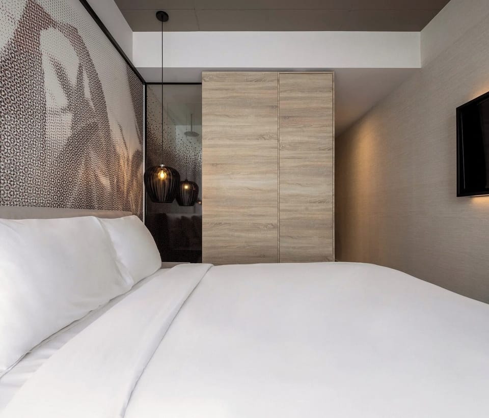 Sink into crisp linens beneath warm pendant lights and calm tones.