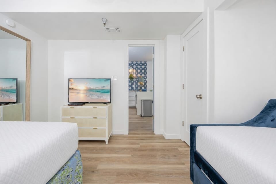 Cozy guest bedroom featuring a TV, stylish decor, and a glimpse of the other accommodations beyond
