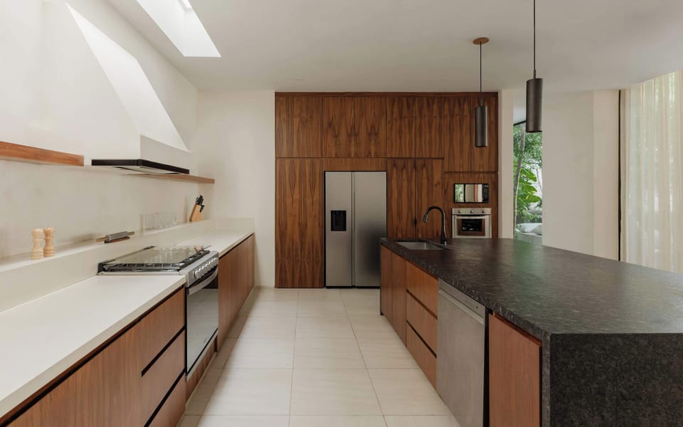 Kitchen with dark countertops, built-in appliances, and stainless steel refrigerator.