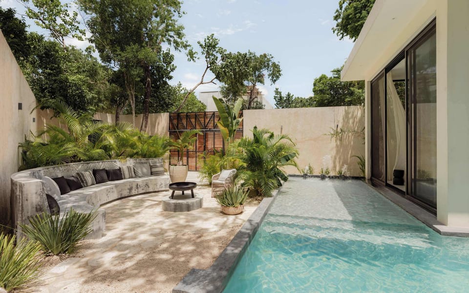 Long private pool with courtyard garden, tropical plants, and white architectural walls.