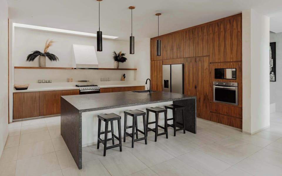 Chef's kitchen with large white island, dark stone countertop, wood cabinets, and bar stools.