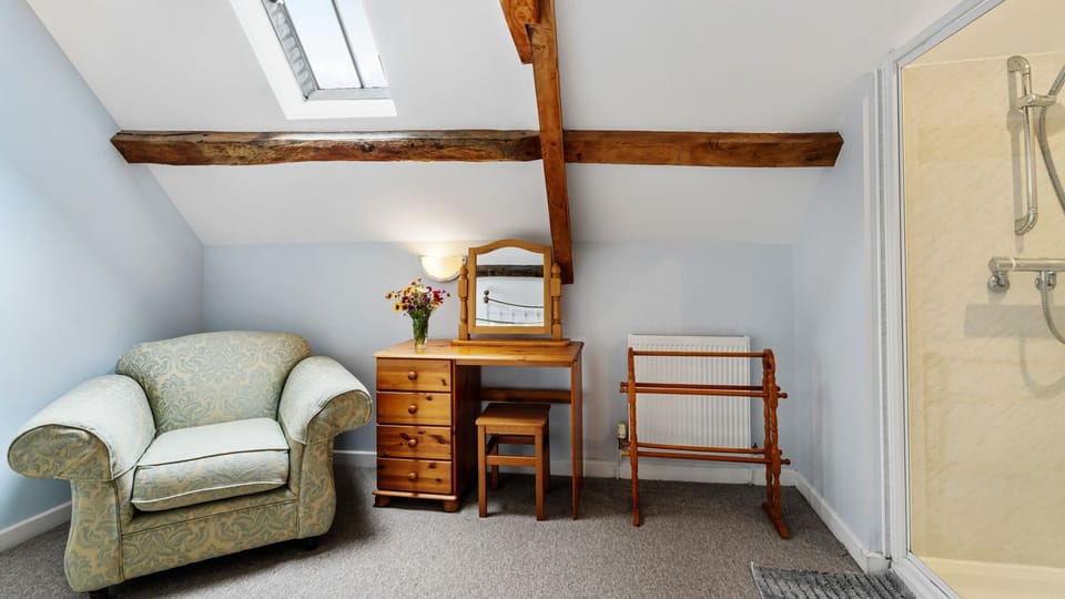 A dressing table and cosy armchair provide extra space in the main bedroom at Kestrel Barn.