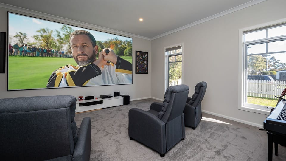 High projector screen in the movie room, with cinema seating