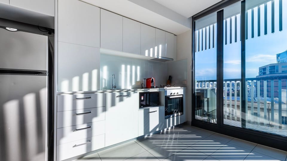 Bright galley kitchen framed by city views and clean minimalist design.