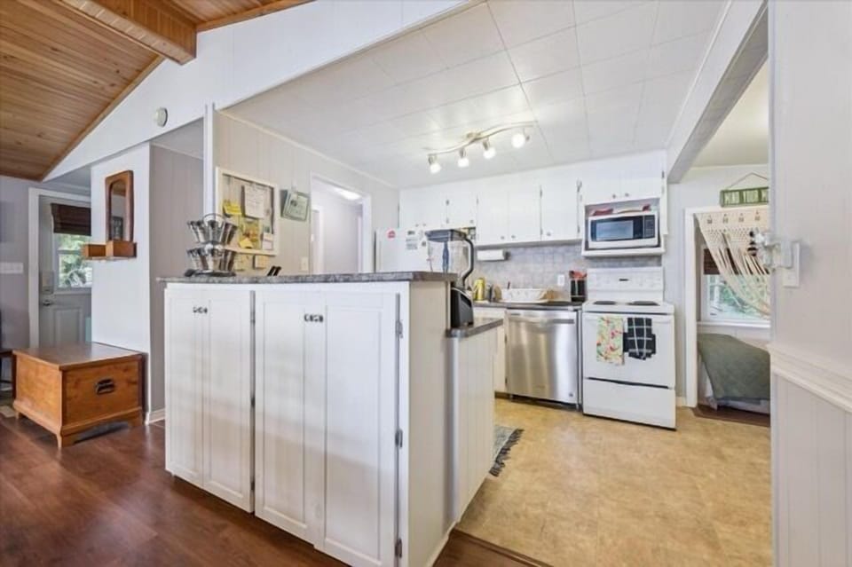 Charming open-concept kitchen with white cabinetry, modern appliances, and a cozy view into the adjoining bedroom.