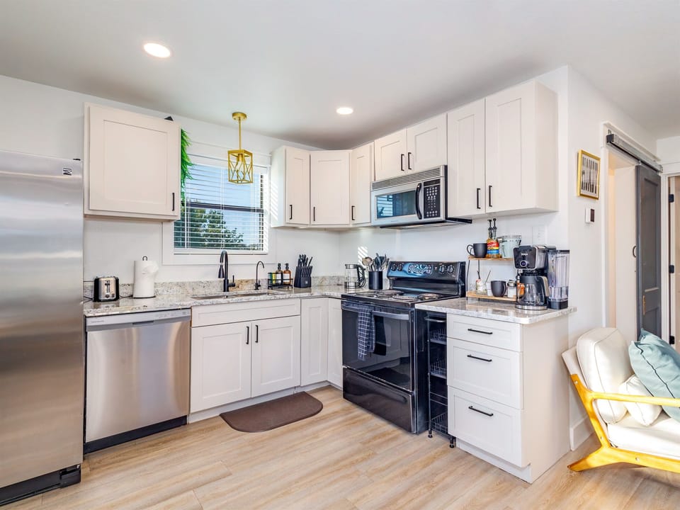 Fully stocked kitchen with everything you need—full-size fridge, stove, microwave, dishwasher, and a coffee bar for your morning brew.