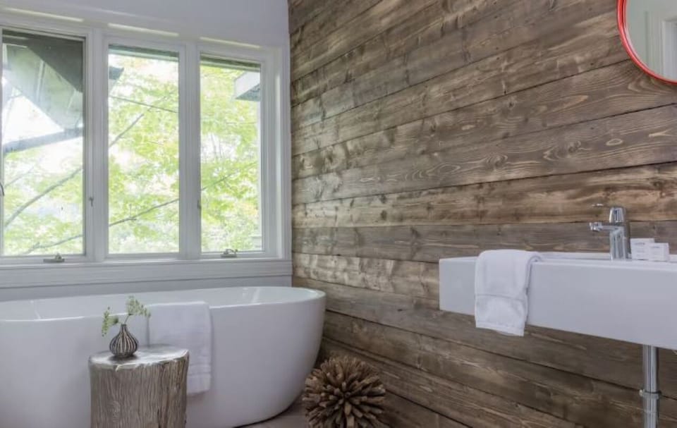 Soak in the serene tub beside rustic wood and treetop views.