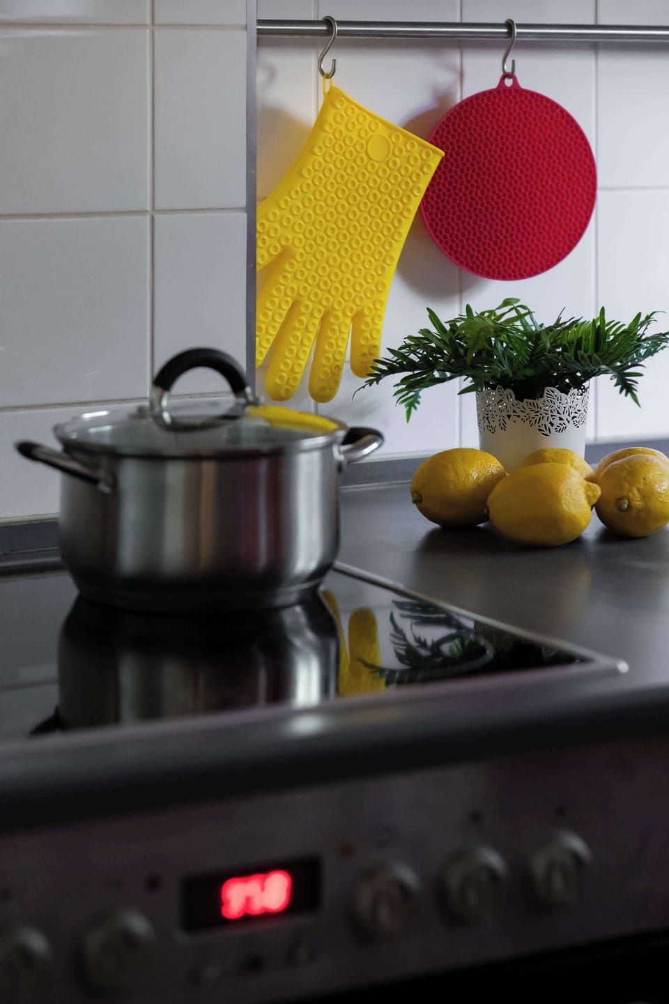 A kitchen counter close-up with a black stovetop, kettle, and a lemon decoration.