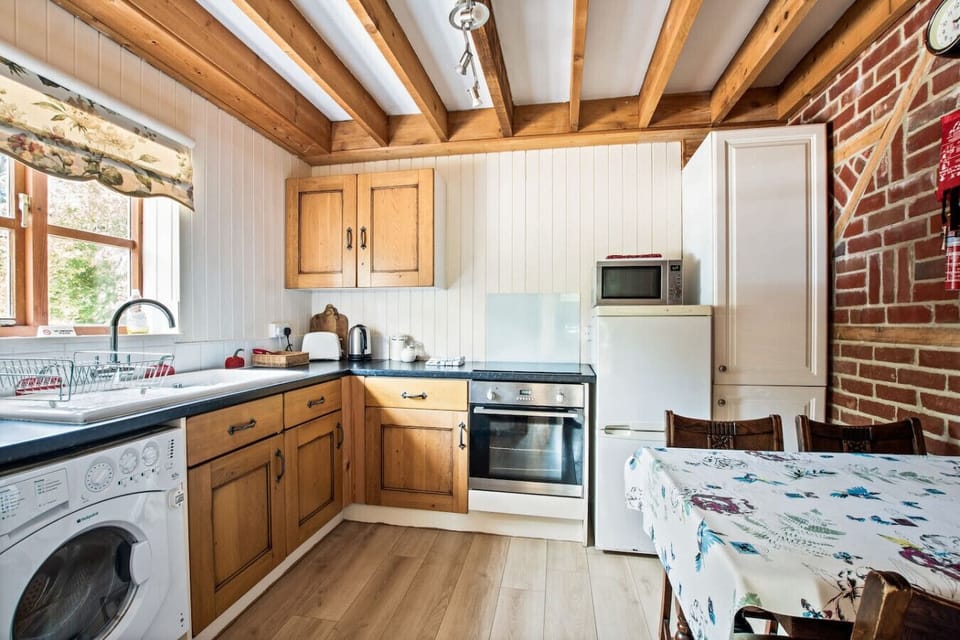 Bright kitchen with microwave, oven and exposed beams