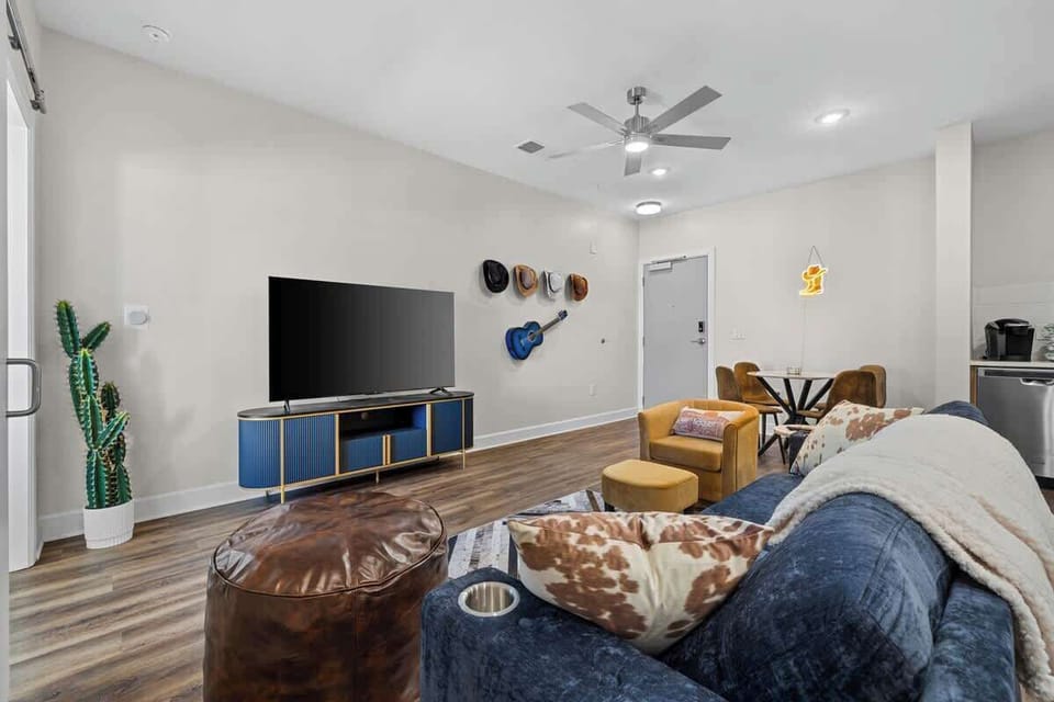 - Spacious living room with large TV perfect for relaxing nights  
- Guitar and hat wall decor adding unique character and style  
- Comfortable seating arranged for easy lounging and gatherings  
