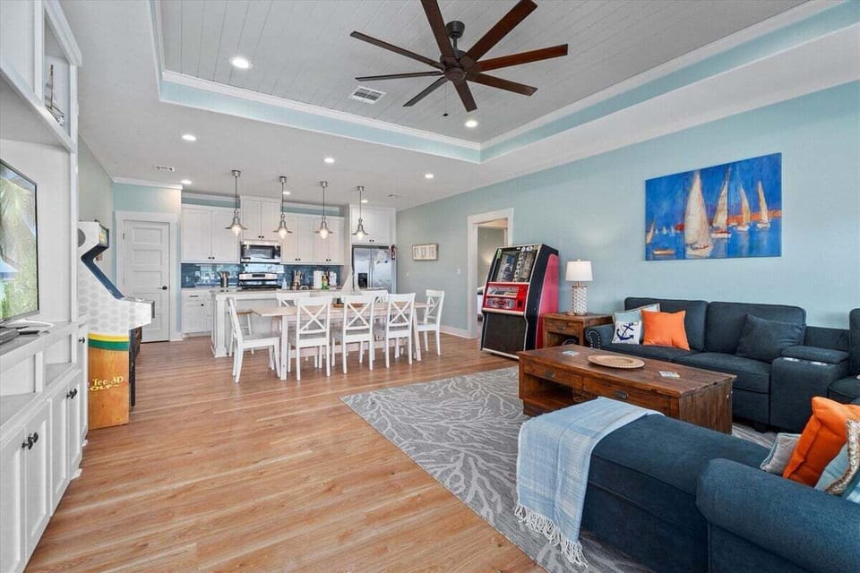 Open-concept living and dining space with comfortable seating, dining table, arcade game, and seamless flow into the kitchen area.