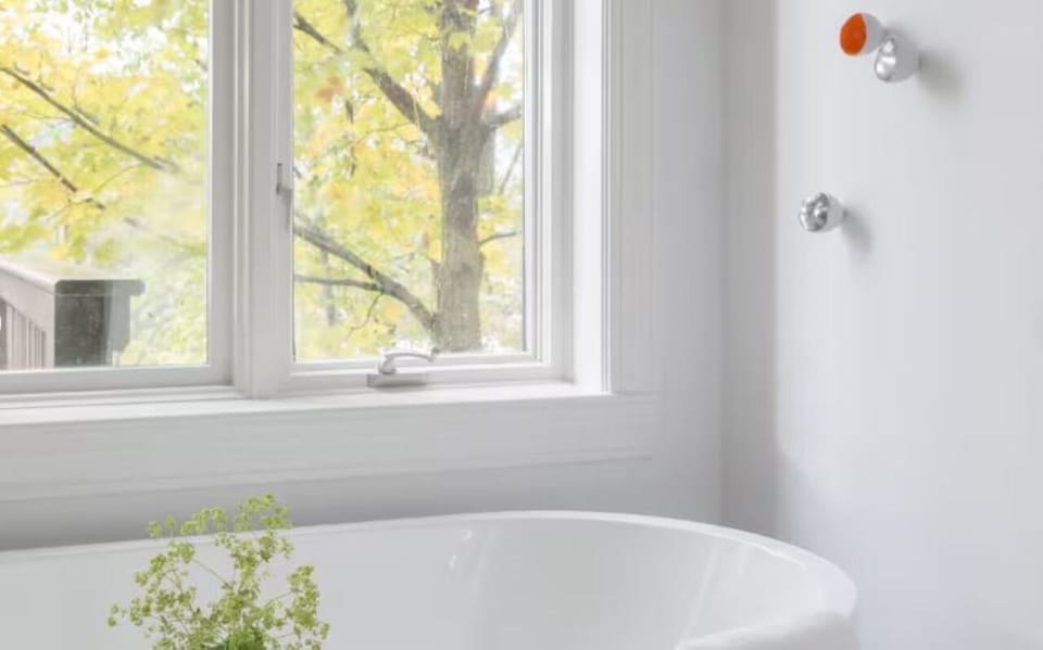 Soak in a deep tub beneath bright, leafy window light.