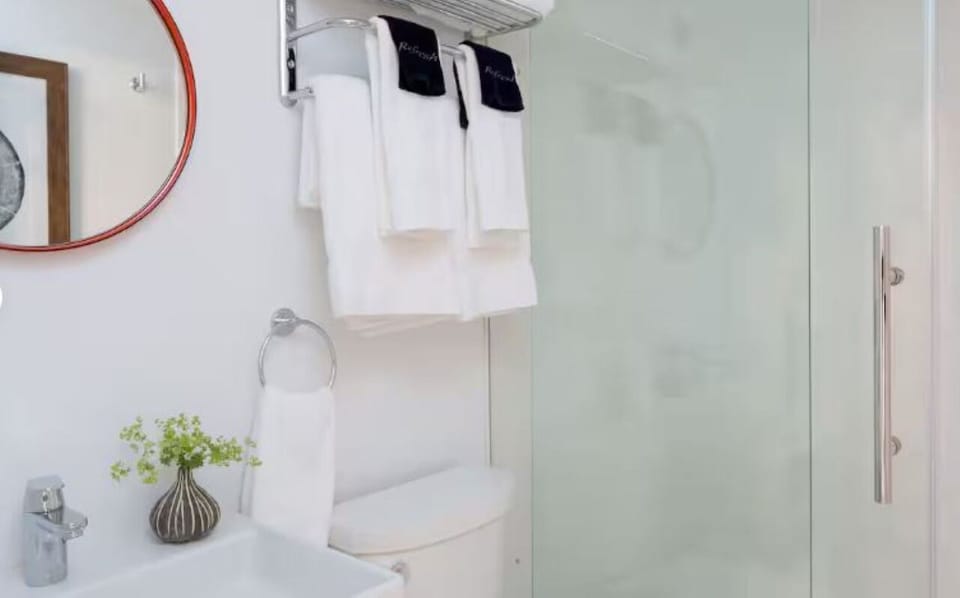 Refresh in a bright, glass-shower bath with fluffy towels.