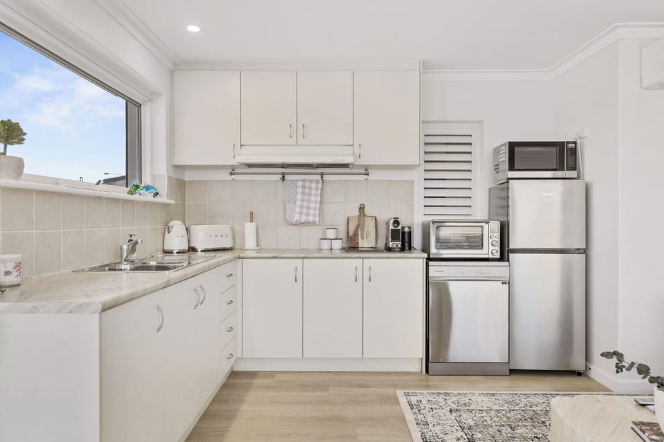 Our bright kitchen has everything you need for a comfortable stay, including modern white cabinets, ample counter space, and stainless steel appliances.